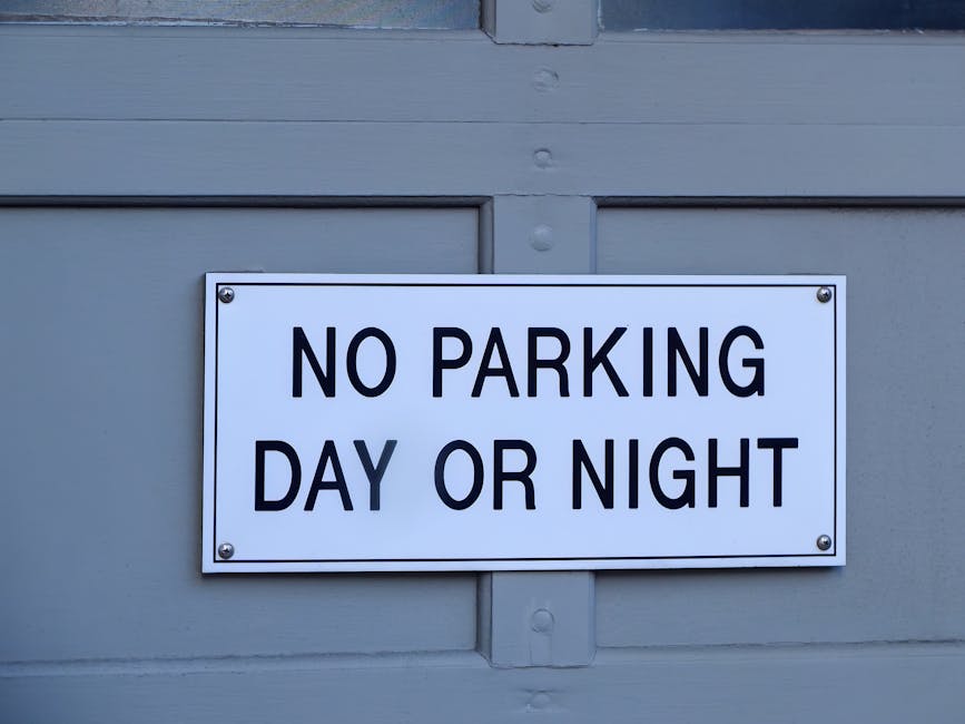 A road closure sign placed on a gravel surface indicating that the road is closed, with the sign resting on a black stand and secured with two small wooden clothespins. The sign has a white background